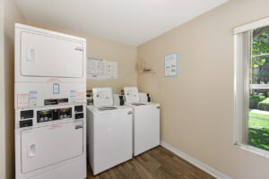 small laundry room with two side by side washers and two stacked dryers