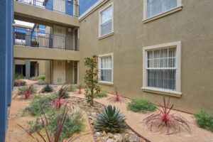 Exterior Overlook at Anaheim Hills, beige and blue residential buildings, meticulous landscaping, bench along sidewalk, lush foliage.