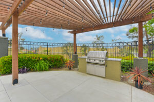 Exterior Grilling area, pergola, meticulous landscaping, photo taken on a sunny day.