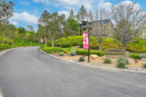 Exterior signage Overlook at Anaheim Hills, meticulous landscaping, view of the road leading to apartment complex at the top of the hill.