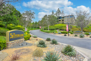 Exterior signage Overlook at Anaheim Hills, meticulous landscaping, view of the road leading to apartment complex at the top of the hill.